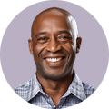 bg-client-review-2 - beachfrontcondopattaya Smiling man in a light blue checkered shirt, portrait against a lavender circular background.