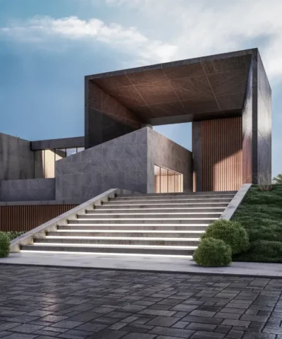 Modern concrete building with a large rectangular frame, reached by illuminated stairs and well-kept landscaping on a sloped site.