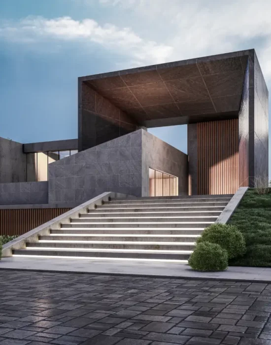 Modern concrete building with a large rectangular frame, reached by illuminated stairs and well-kept landscaping on a sloped site.
