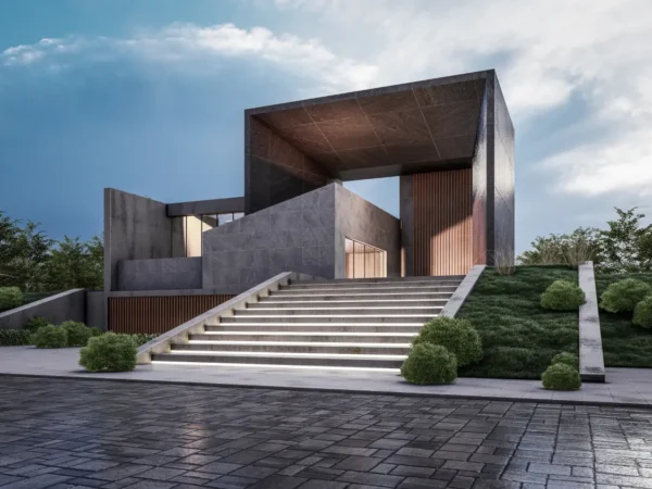 Modern concrete building with a large rectangular frame, reached by illuminated stairs and well-kept landscaping on a sloped site.