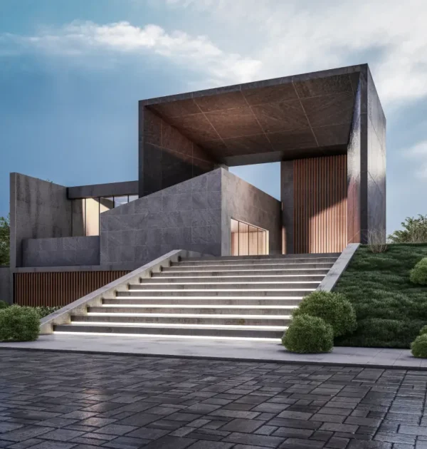 Modern concrete building with a large rectangular frame, reached by illuminated stairs and well-kept landscaping on a sloped site.