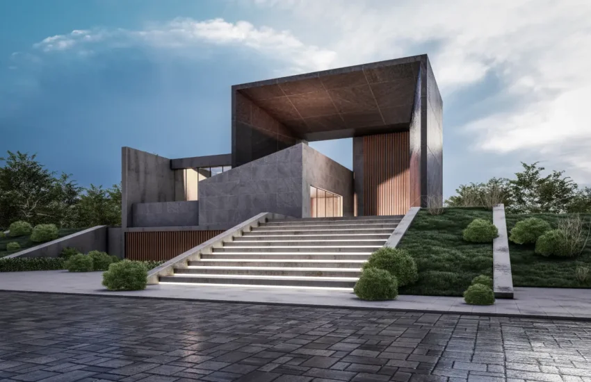 Modern concrete building with a large rectangular frame, reached by illuminated stairs and well-kept landscaping on a sloped site.