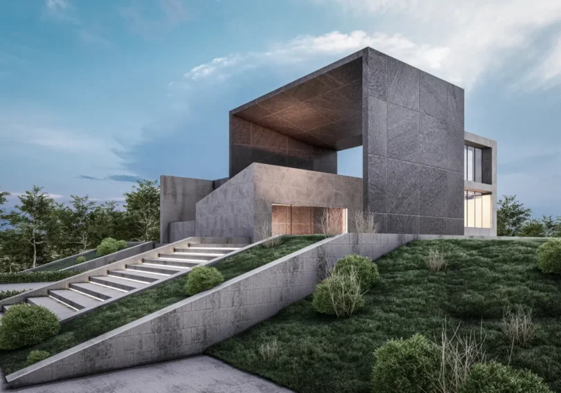 Modern concrete house on a terraced hillside with wide staircase and manicured shrubbery, under a blue sky.