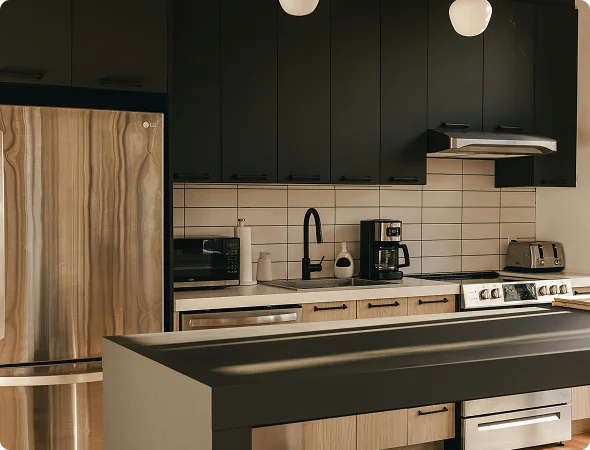Modern kitchen scene with dark upper cabinets, light lower cabinets, a stainless fridge, and an island in the foreground.